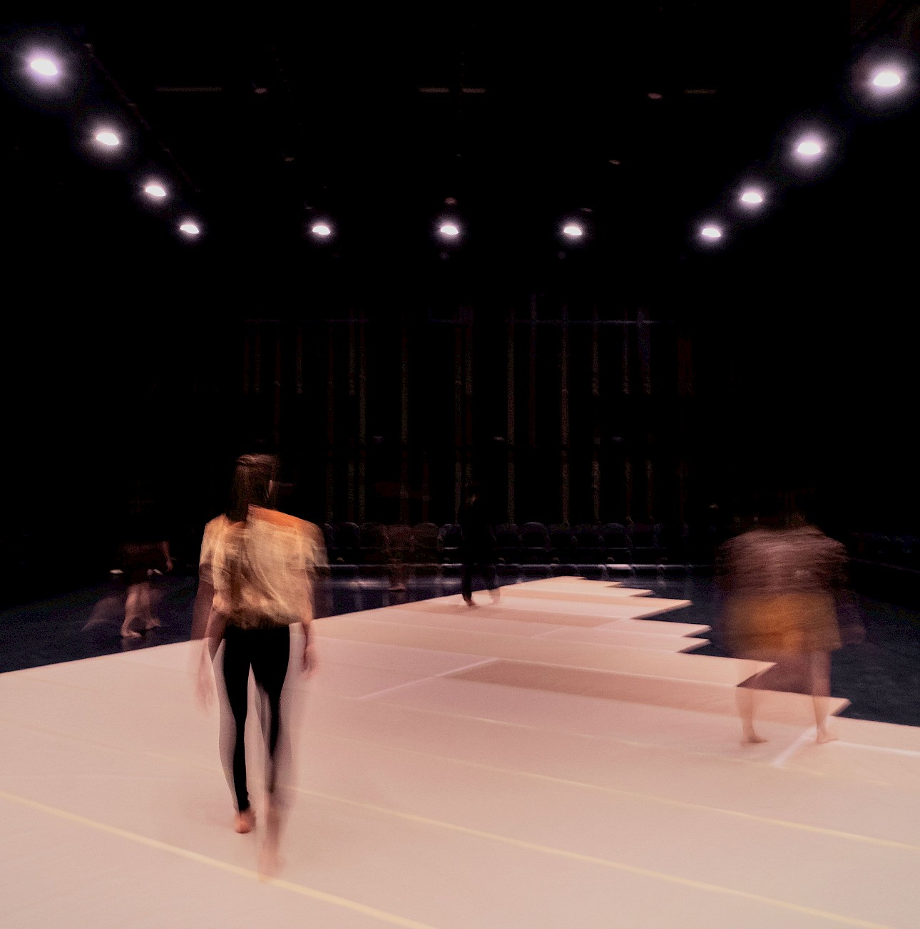 ALKANARA - Several individuals walking together on a stage, engaged in a presentation or performance. - ©João Octávio Peixoto / Festival DDD